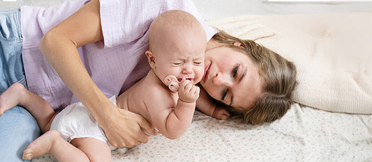 Un bébé pleure dans les bras de sa mère.